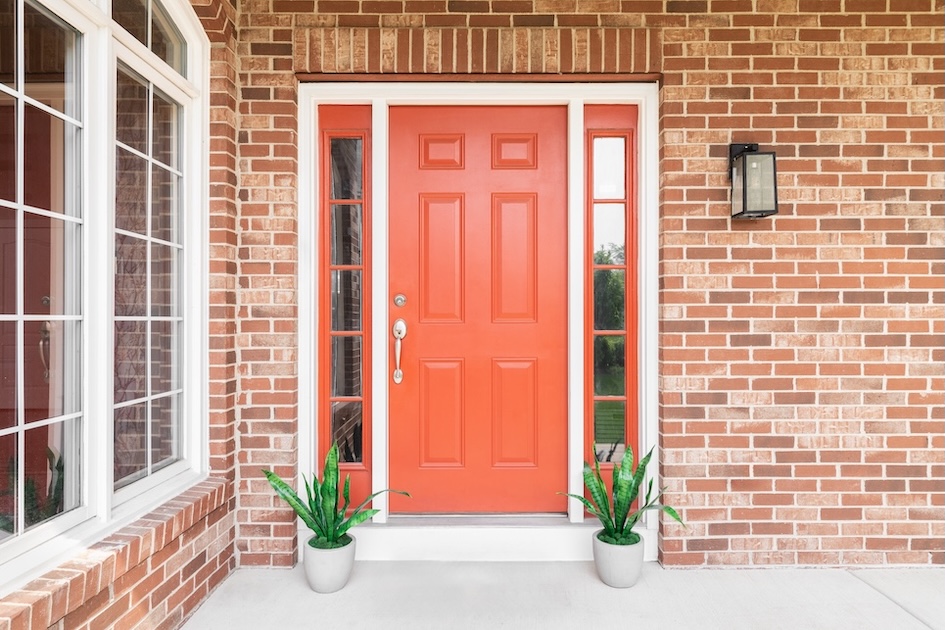 red front entry door with two small plants